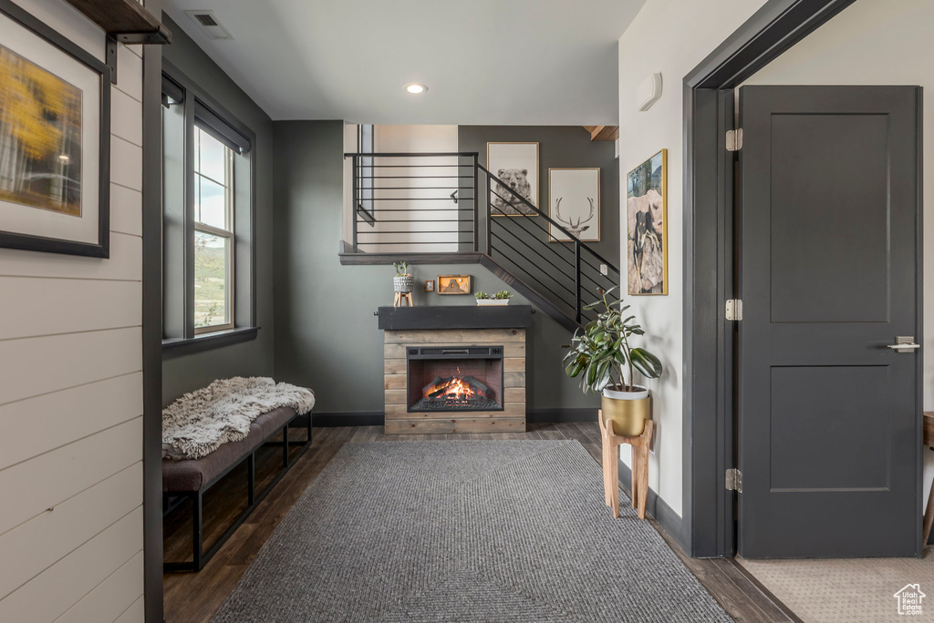 Living area featuring wood finished floors, stairs, baseboards, recessed lighting, and a warm lit fireplace