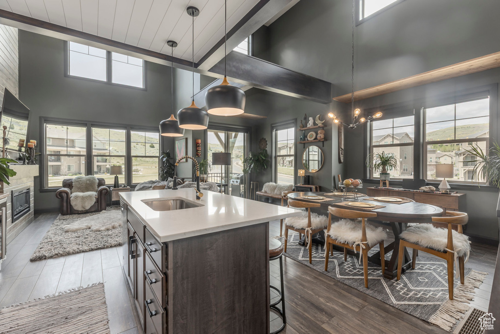 Kitchen featuring open floor plan, a sink, dark wood-style flooring, a towering ceiling, and a kitchen bar