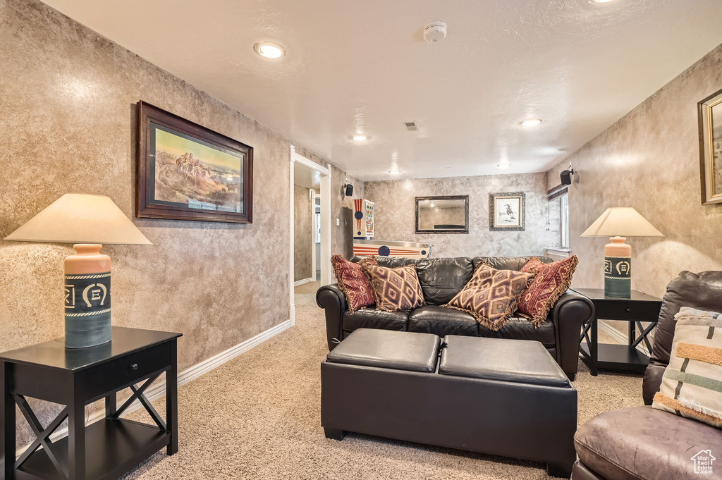 Carpeted living area featuring baseboards, a textured wall, and recessed lighting