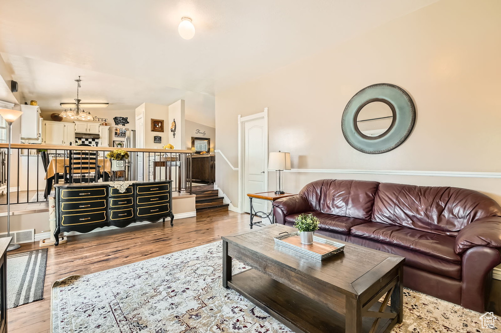 Living area featuring wood finished floors, a chandelier, stairs, and baseboards