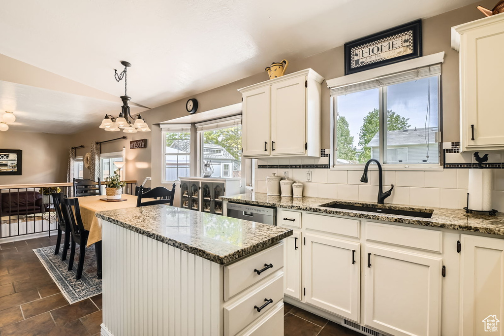 Kitchen with a sink, decorative backsplash, lofted ceiling, healthy amount of natural light, and a chandelier