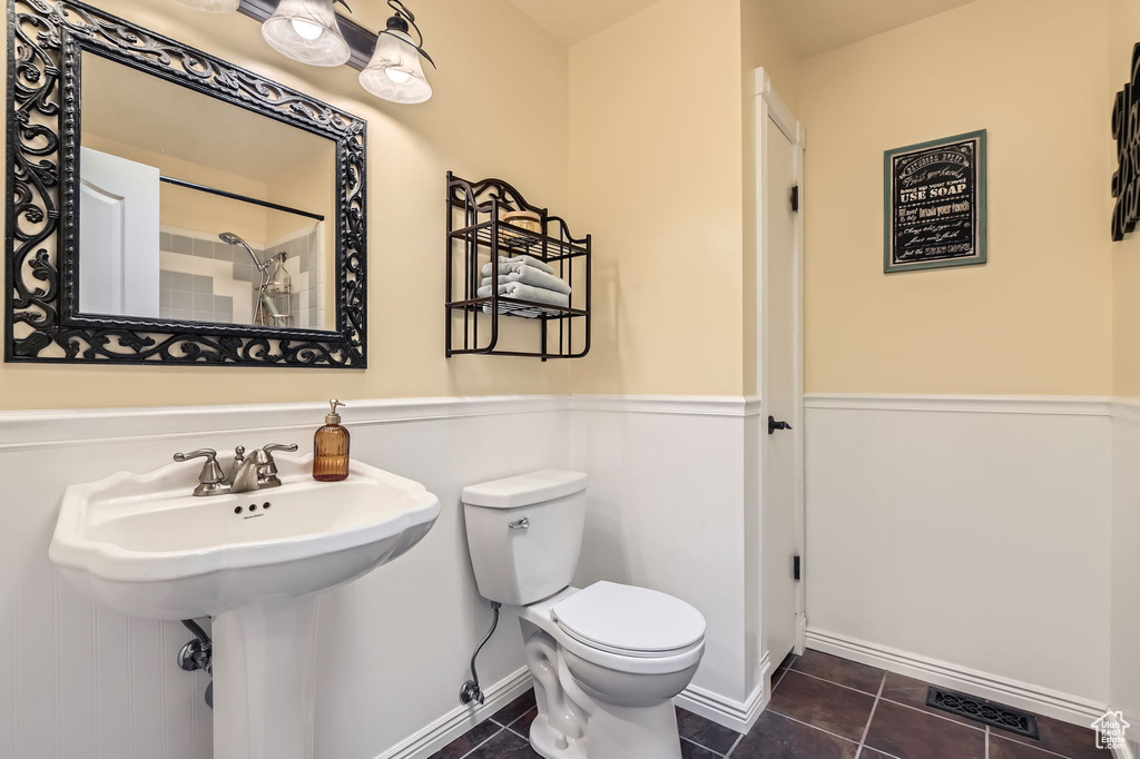 Full bath with toilet, tile patterned floors, baseboards, a shower, and a sink