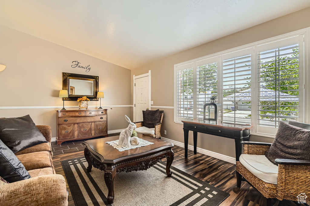 Living area with vaulted ceiling, baseboards, and dark wood finished floors