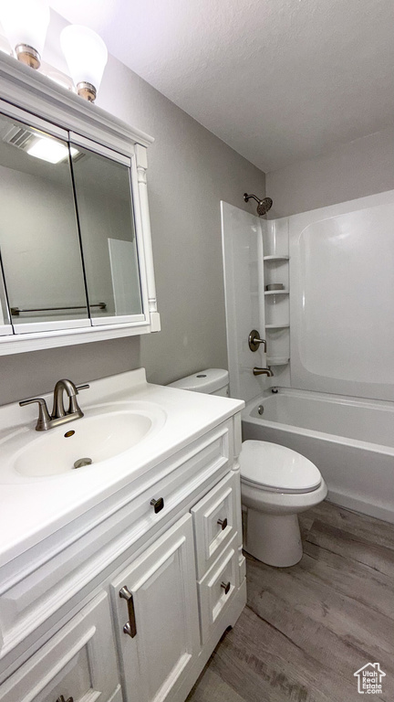 Bathroom with toilet, vanity, wood finished floors, and shower / tub combination