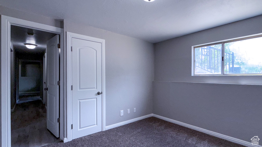 Unfurnished bedroom featuring dark carpet and baseboards
