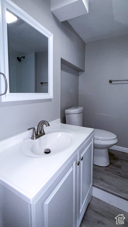 Bathroom with toilet, vanity, wood finished floors, and baseboards