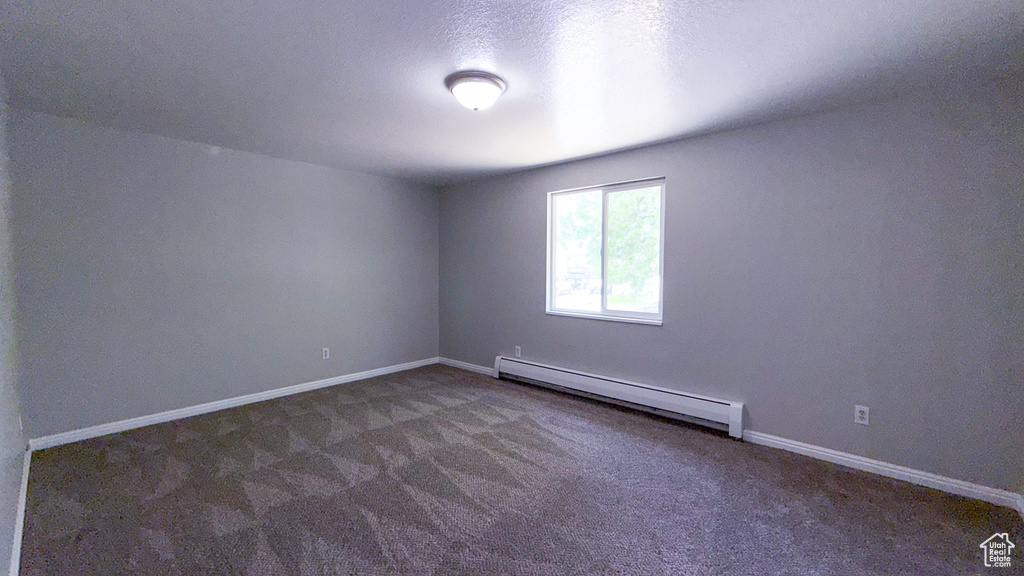 Unfurnished room featuring a baseboard radiator, carpet flooring, and baseboards