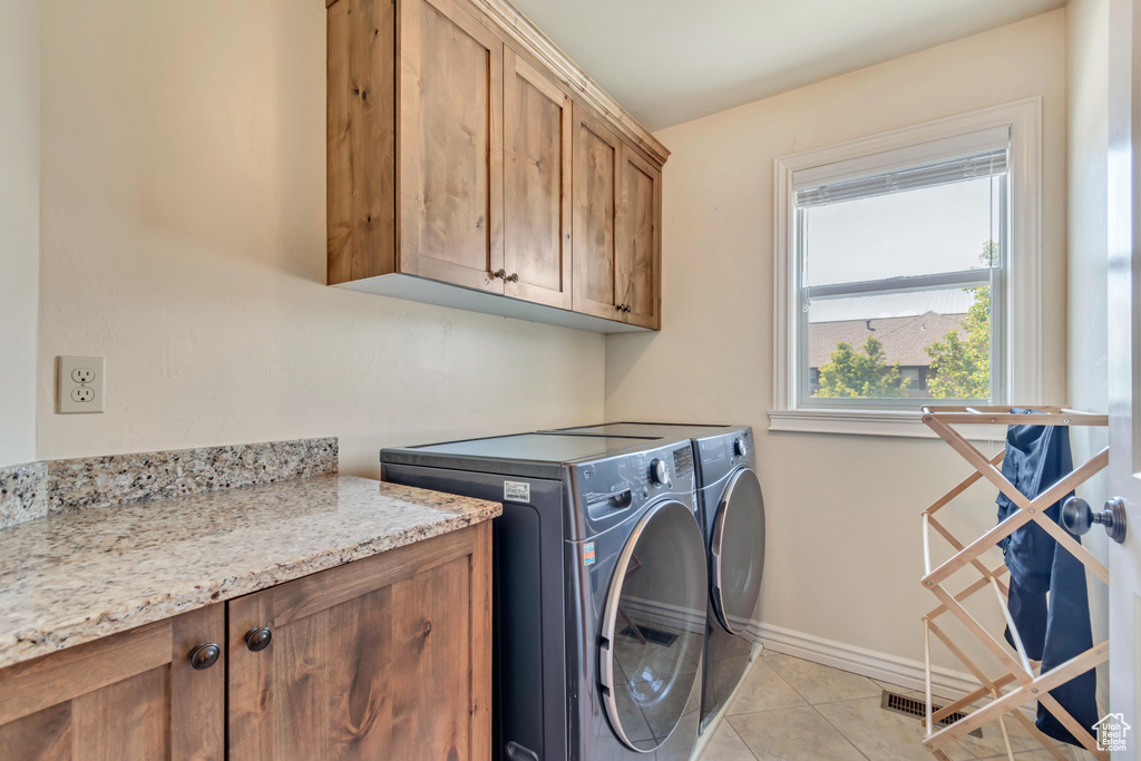 Laundry area featuring cabinet space, independent washer and dryer, light tile patterned floors, and baseboards