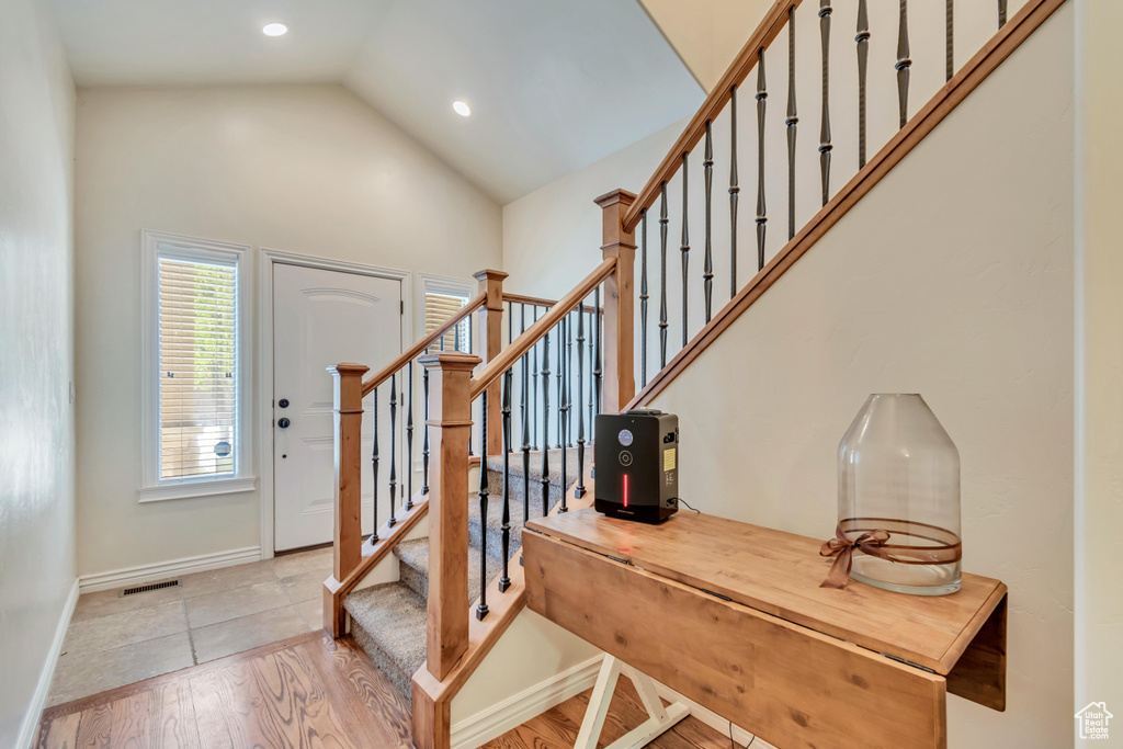 Foyer with stairway, light wood-type flooring, recessed lighting, baseboards, and high vaulted ceiling