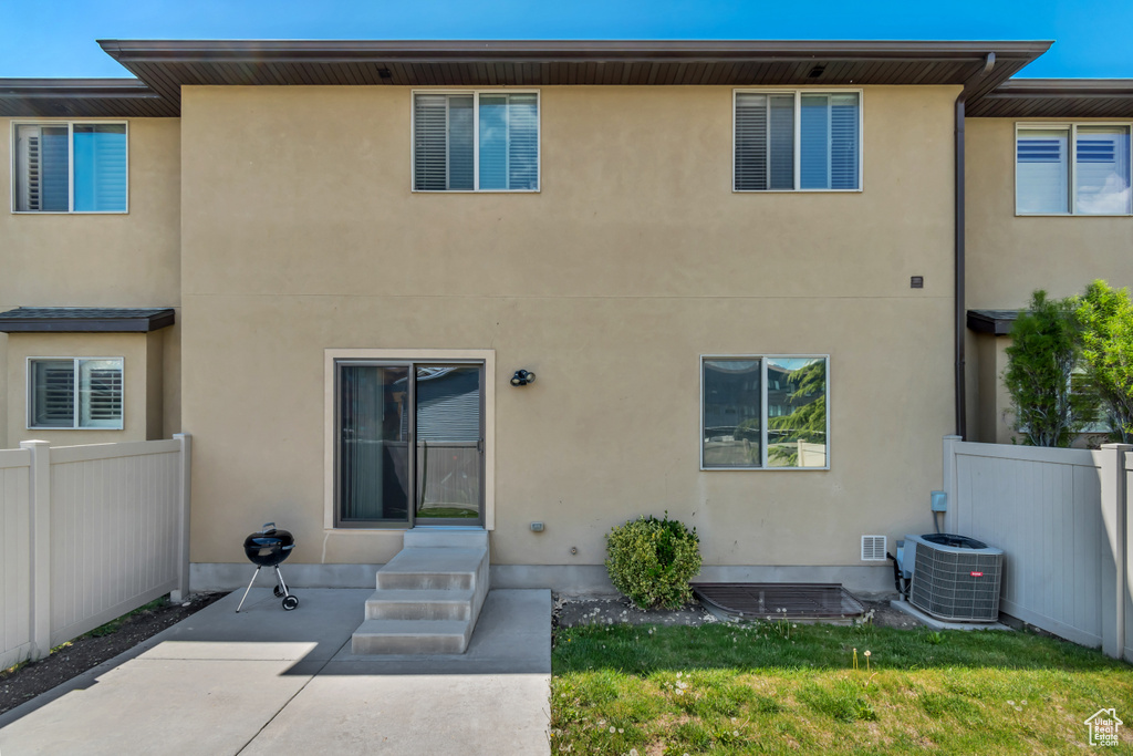 Rear view of house with a patio, stucco siding, and central air condition unit