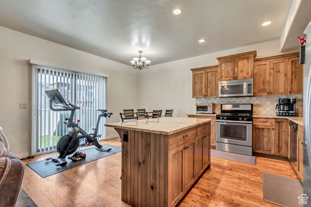 Kitchen with stainless steel appliances, light wood-style flooring, a chandelier, tasteful backsplash, and recessed lighting