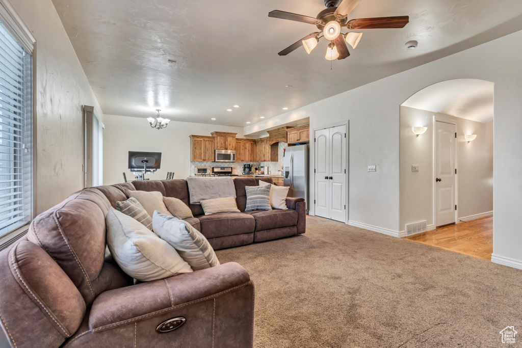 Living area with arched walkways, light colored carpet, ceiling fan, baseboards, and recessed lighting