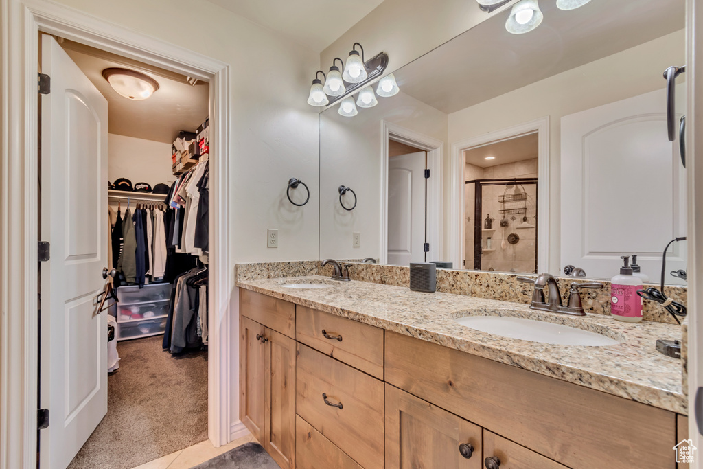 Bathroom featuring a shower stall, double vanity, and a spacious closet