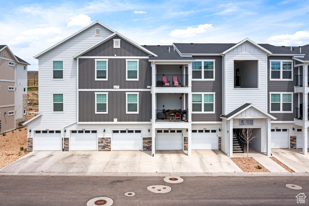 View of front facade featuring board and batten siding, an attached garage, and driveway