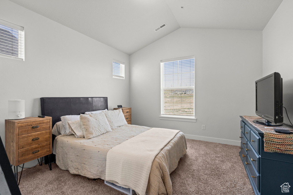 Bedroom with lofted ceiling, light carpet, and baseboards