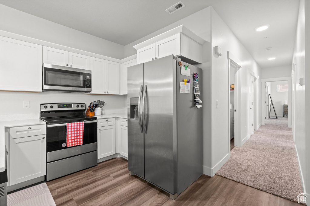 Kitchen featuring stainless steel appliances, white cabinetry, wood finished floors, light countertops, and recessed lighting