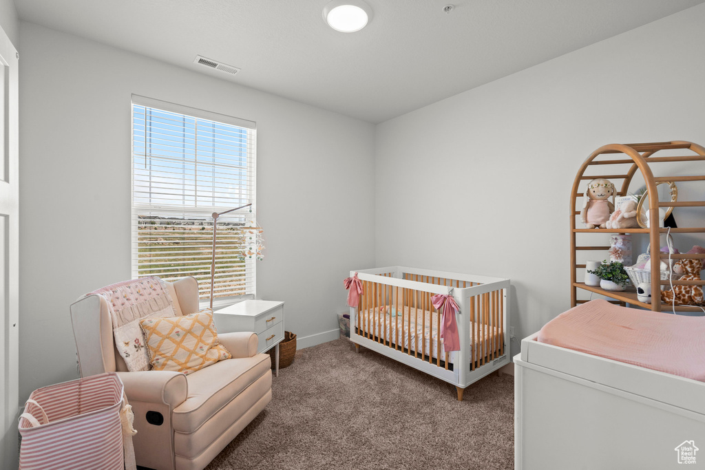 Bedroom with carpet floors, a crib, and baseboards