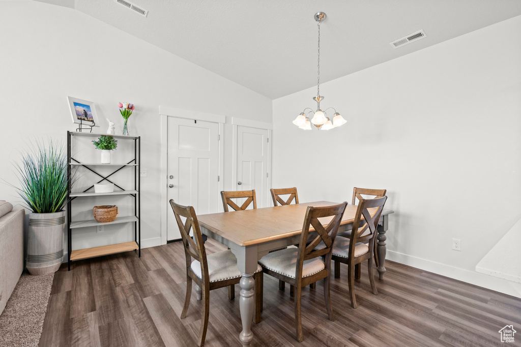 Dining area featuring a chandelier, vaulted ceiling, wood finished floors, and baseboards