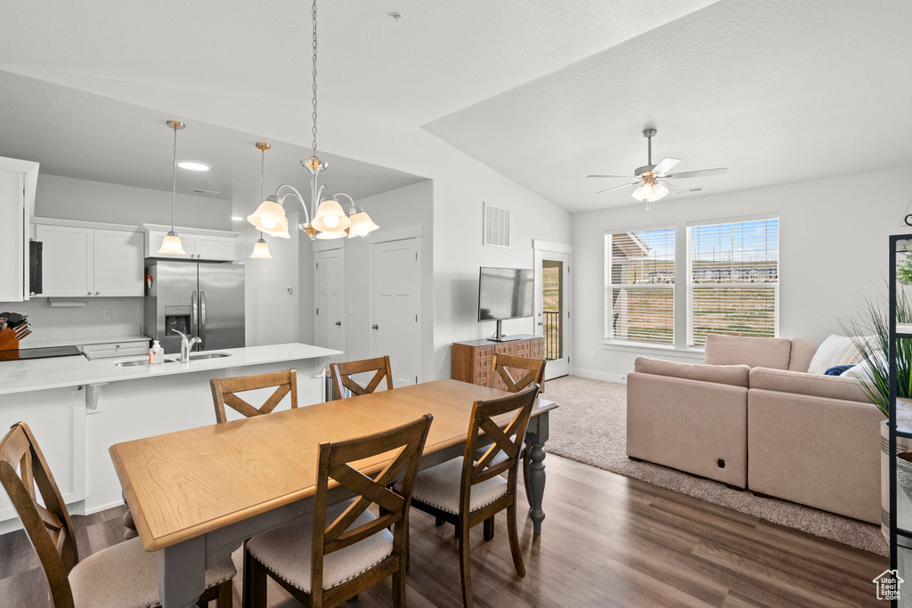 Dining room with a ceiling fan, dark wood-type flooring, vaulted ceiling, a chandelier, and baseboards
