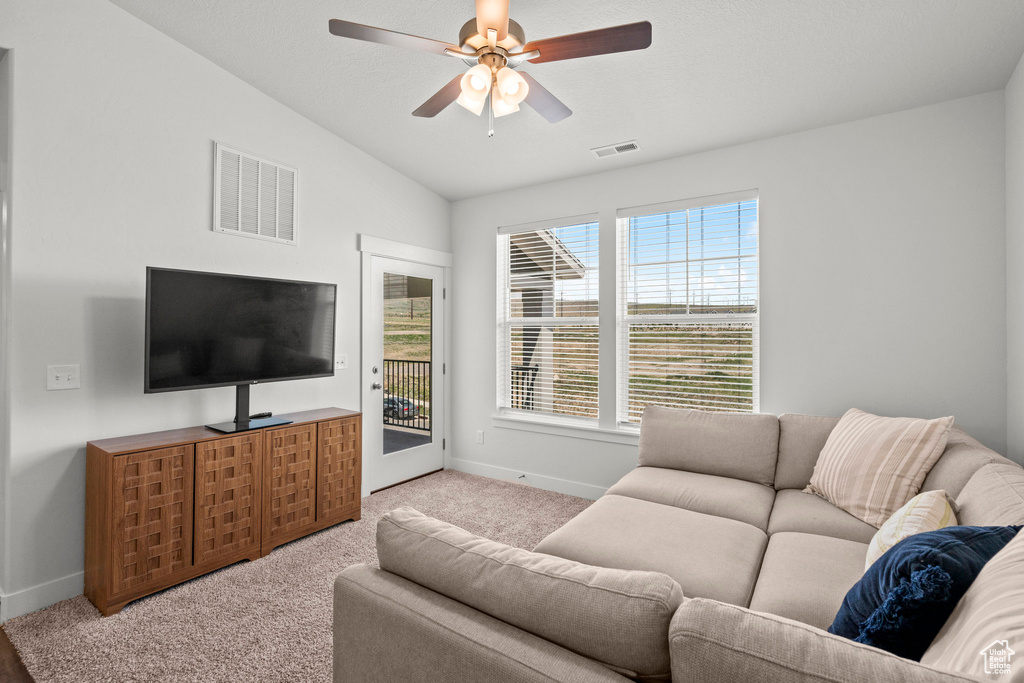 Carpeted living area with baseboards, ceiling fan, and vaulted ceiling