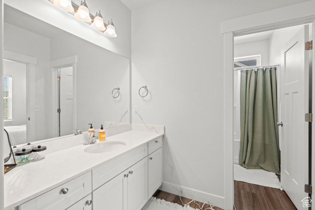 Bathroom with vanity, wood finished floors, curtained shower, and baseboards