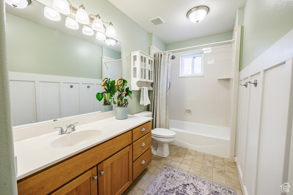 Bathroom with vanity, shower / bathtub combination with curtain, toilet, and tile patterned floors