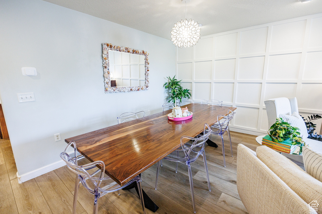 Dining room featuring light wood-style flooring, a chandelier, and baseboards