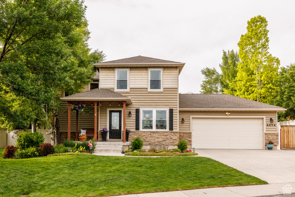 View of front facade featuring a garage, concrete driveway, stone siding, and roof with shingles