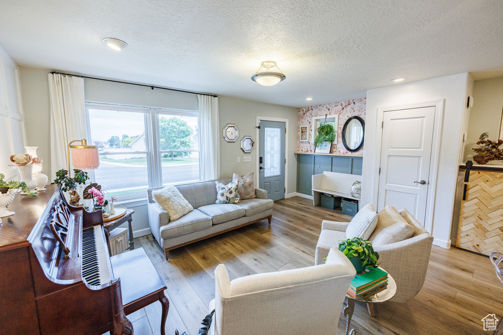Living room with a textured ceiling, wood finished floors, recessed lighting, and baseboards