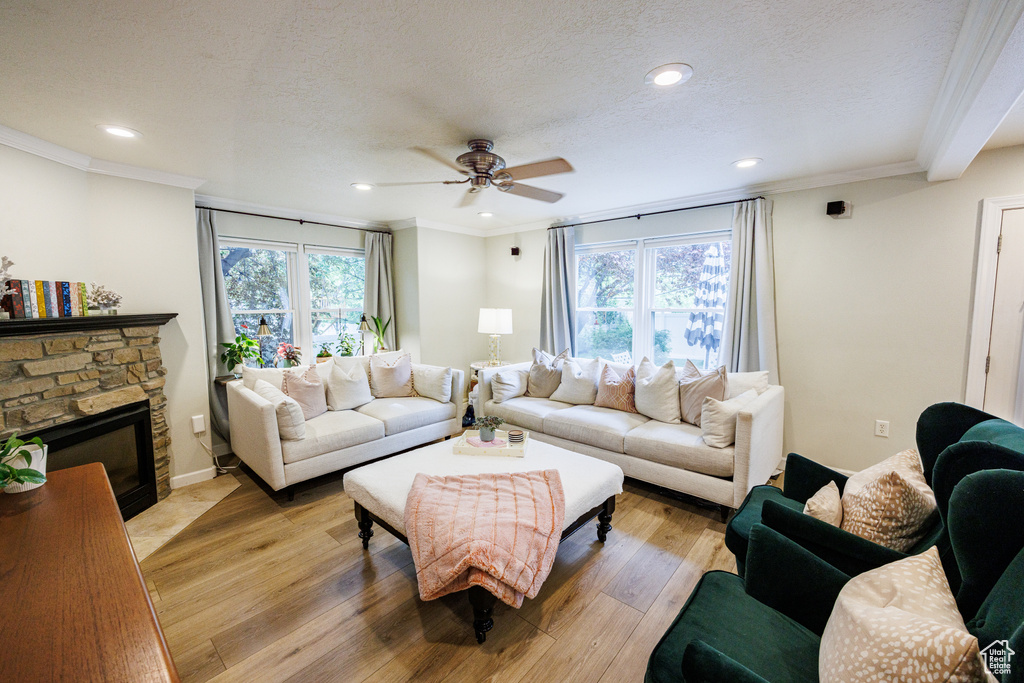 Living area with a ceiling fan, light wood finished floors, recessed lighting, a fireplace, and crown molding