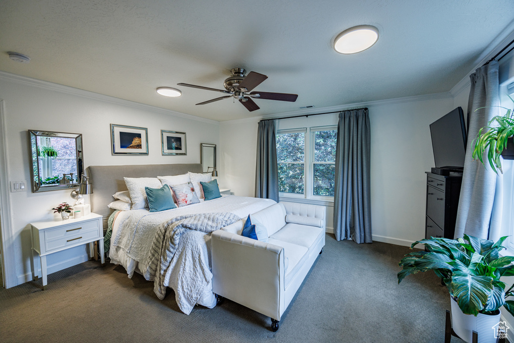 Bedroom featuring crown molding, dark carpet, baseboards, and ceiling fan