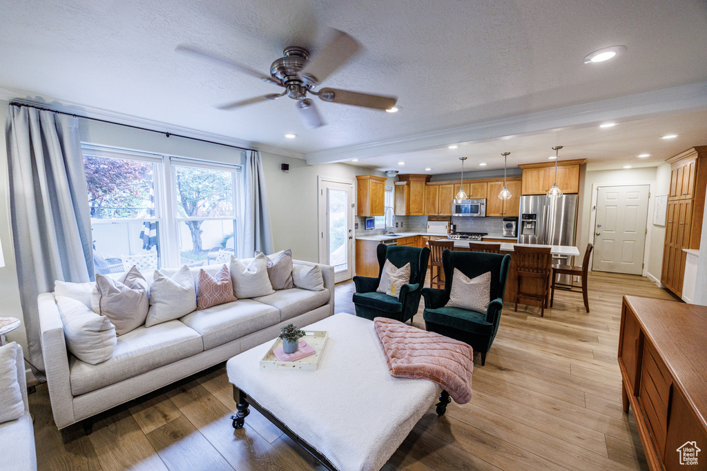Living area with ceiling fan, light wood-style floors, recessed lighting, and a textured ceiling
