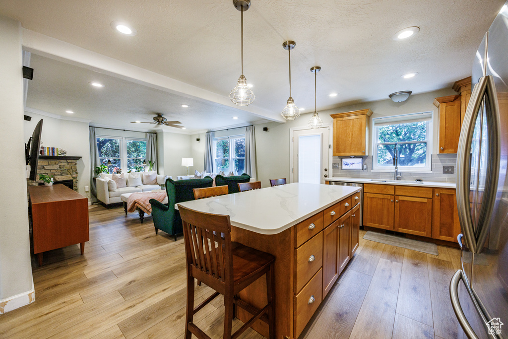 Kitchen featuring freestanding refrigerator, brown cabinets, light countertops, light wood-style floors, and recessed lighting
