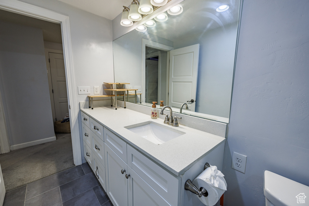 Bathroom with vanity, toilet, tile patterned floors, and baseboards