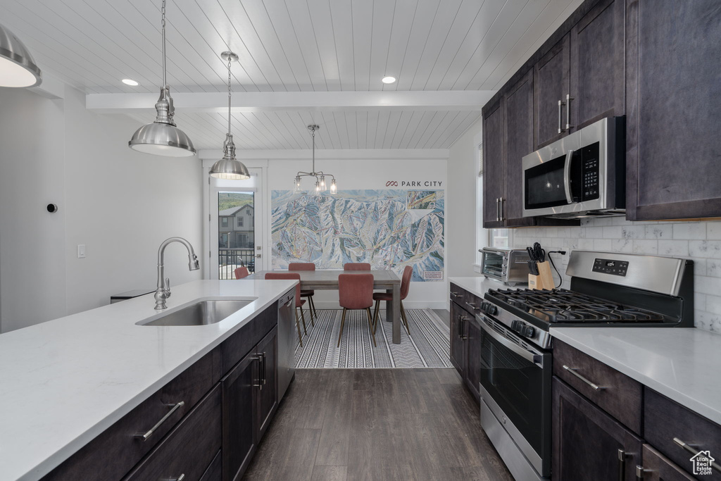 Kitchen featuring stainless steel appliances, a sink, light countertops, dark wood finished floors, and backsplash