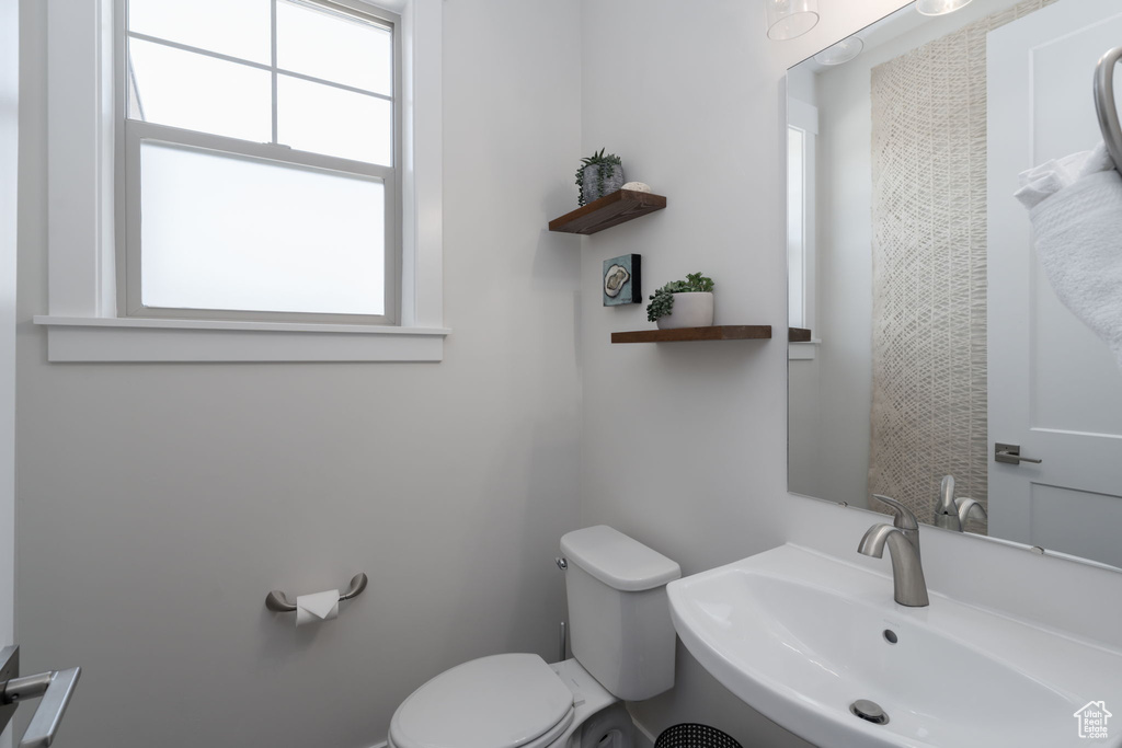 Bathroom with a sink, toilet, and healthy amount of natural light