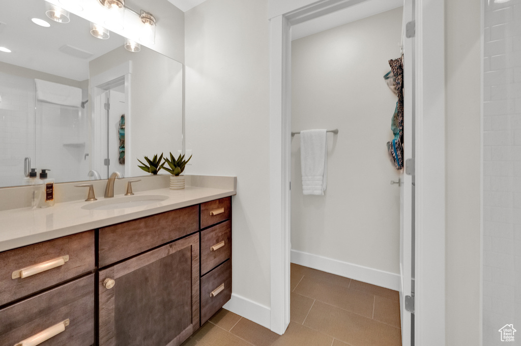 Bathroom featuring vanity, tile patterned floors, a shower, and baseboards