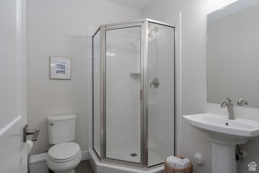 Bathroom featuring a shower stall, toilet, and a sink