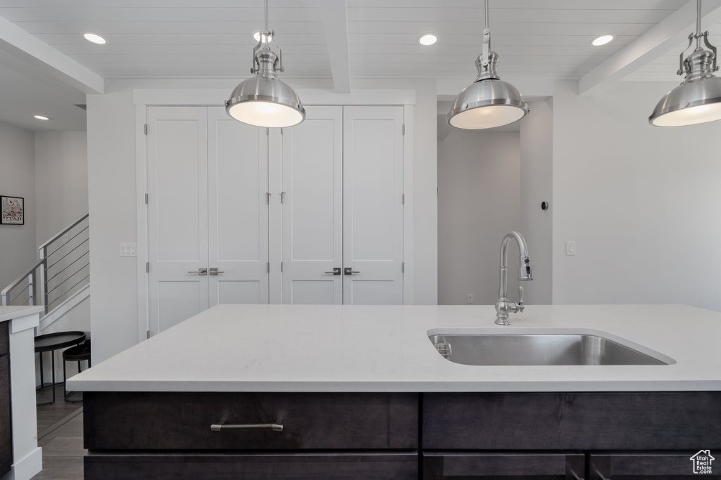 Kitchen with a sink, light countertops, recessed lighting, pendant lighting, and wooden ceiling with exposed beams