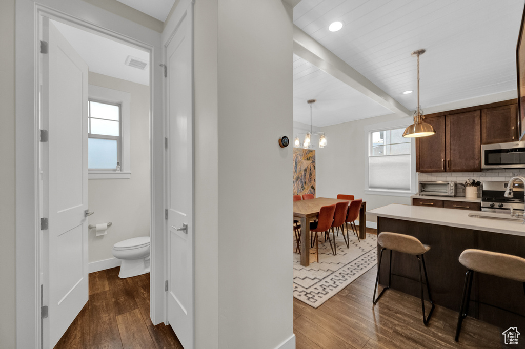 Kitchen featuring appliances with stainless steel finishes, dark brown cabinets, dark wood-style floors, baseboards, and beamed ceiling