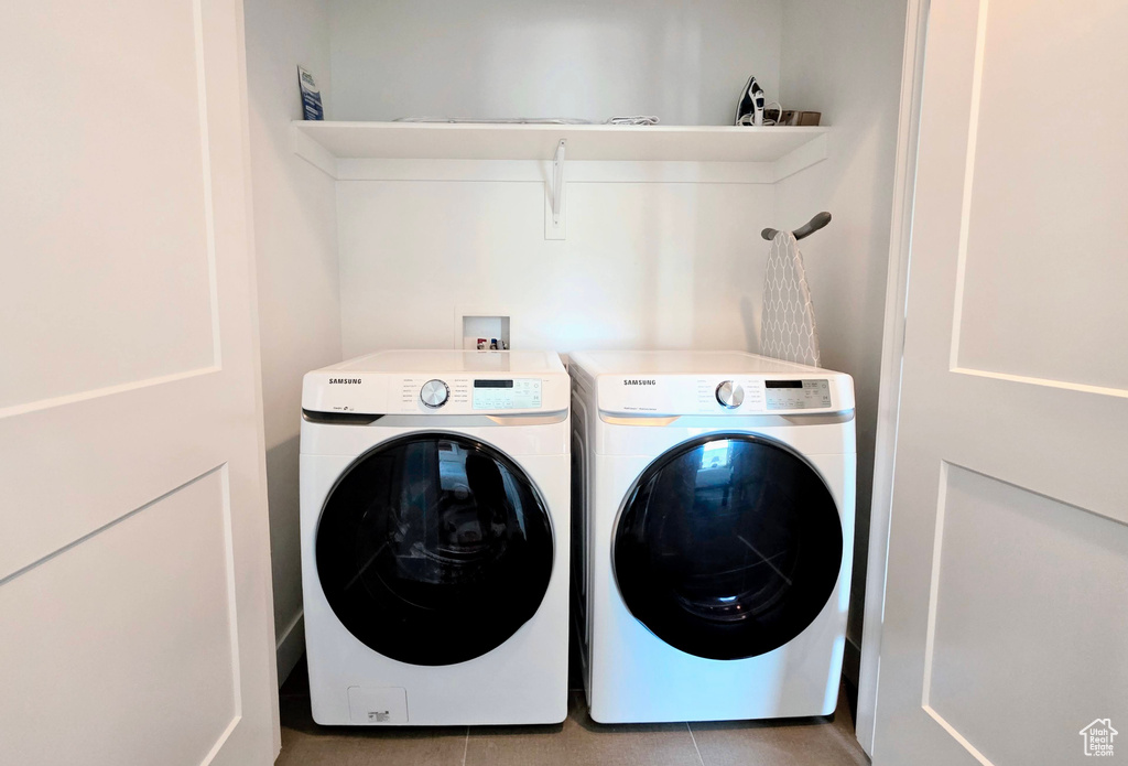 Washroom with washing machine and clothes dryer and light tile patterned flooring