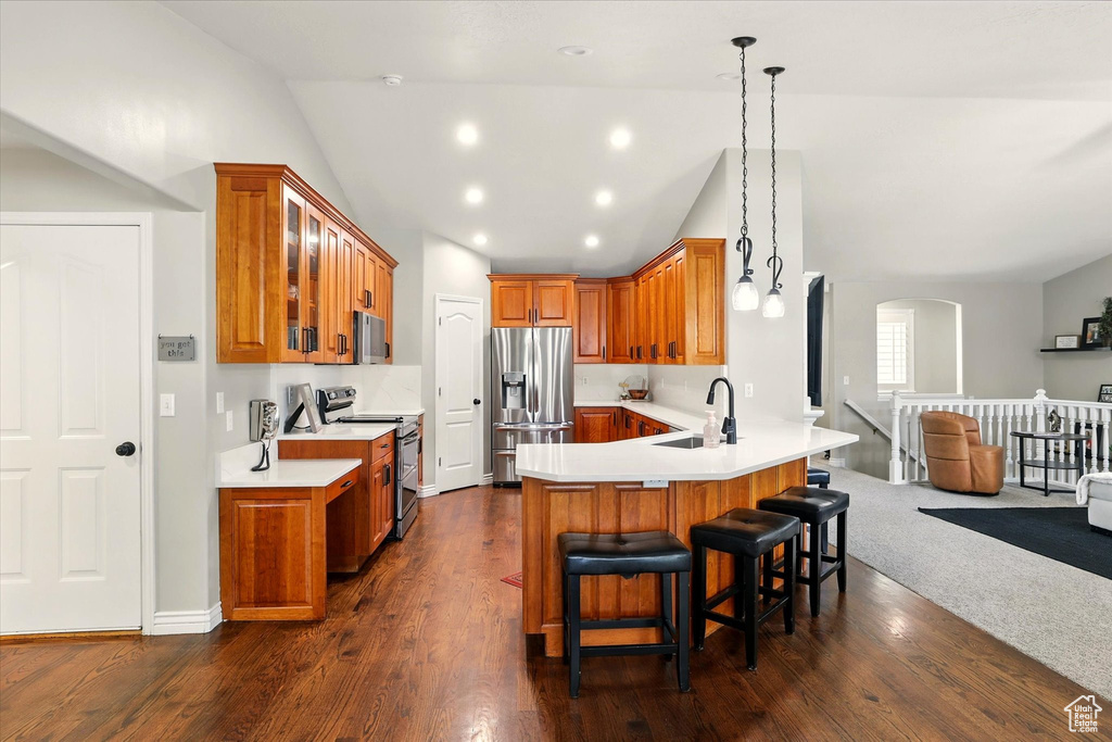 Kitchen with stainless steel appliances, brown cabinetry, a peninsula, glass insert cabinets, and high vaulted ceiling