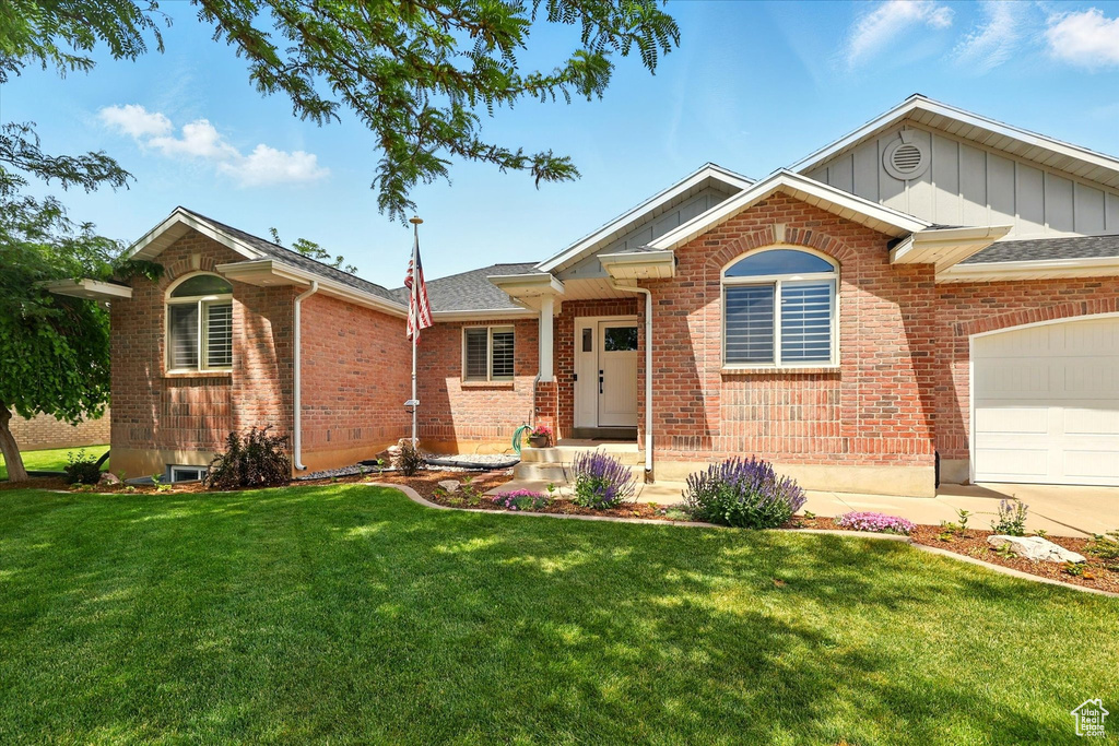 Ranch-style home featuring an attached garage, a front yard, board and batten siding, brick siding, and a shingled roof