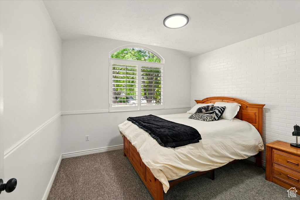 Carpeted bedroom with vaulted ceiling and baseboards