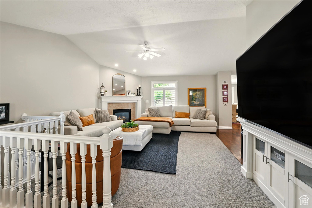 Living area with a tile fireplace, a ceiling fan, vaulted ceiling, and baseboards