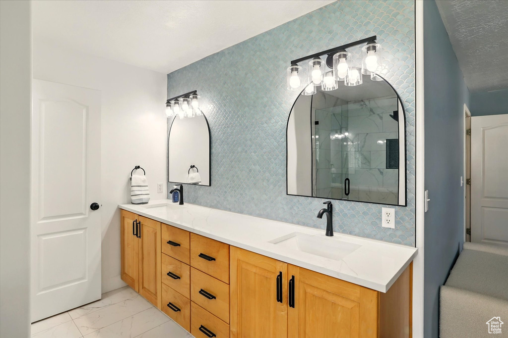 Full bathroom with double vanity, a stall shower, and marble finish flooring
