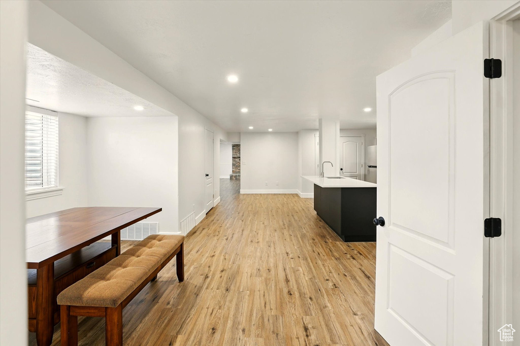 Hall featuring recessed lighting, light wood-style flooring, a sink, and baseboards