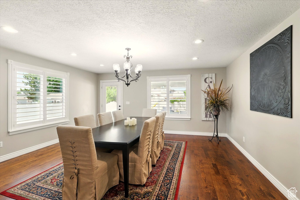 Dining space with a chandelier, dark wood finished floors, a textured ceiling, baseboards, and recessed lighting
