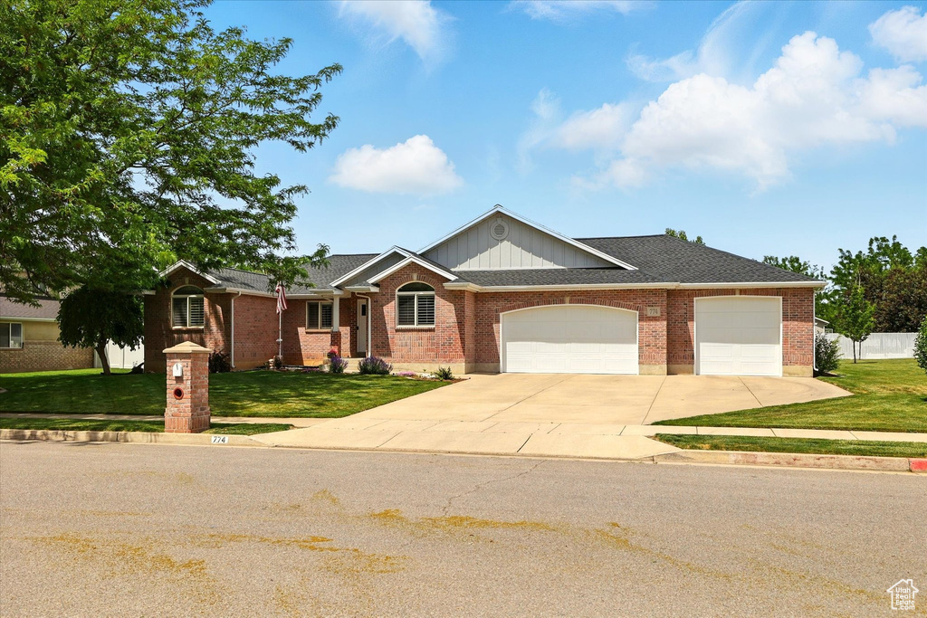 Ranch-style home featuring driveway, a front lawn, an attached garage, and brick siding