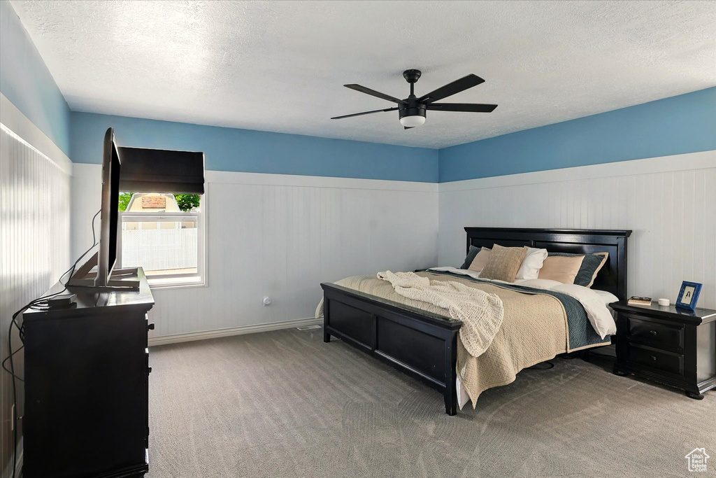 Carpeted bedroom with a textured ceiling and ceiling fan